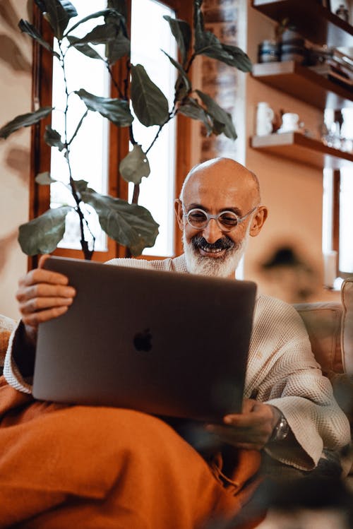 使用macbook的棕色和白色条纹长袖衬衫的男人 · 免费素材图片