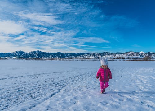 穿白夹克和红色裤子站在雪地上的人 · 免费素材图片