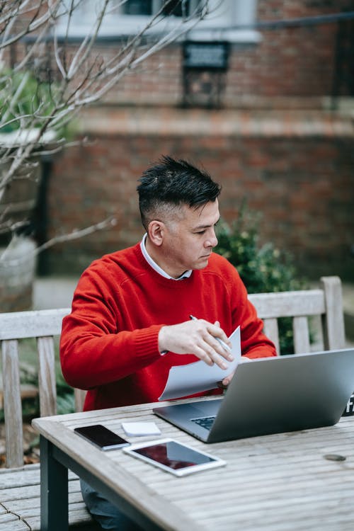 使用macbook Pro的红色毛衣的男人 · 免费素材图片