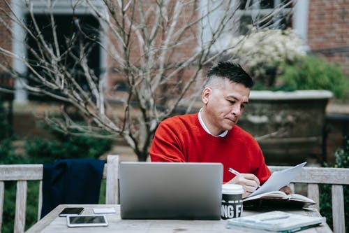 使用macbook Pro的红色毛衣的男人 · 免费素材图片