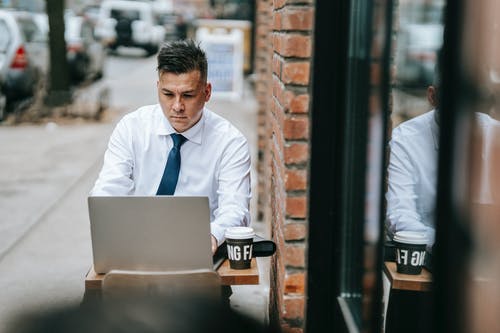 使用银色macbook的白色礼服衬衫的男人 · 免费素材图片