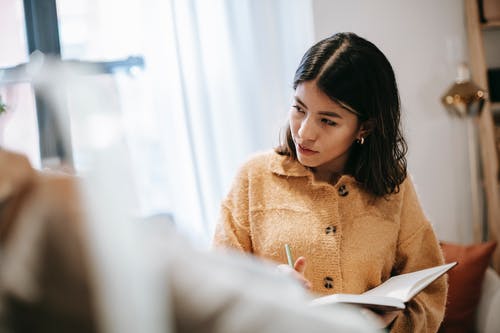 坐在椅子上的棕色外套的女人 · 免费素材图片