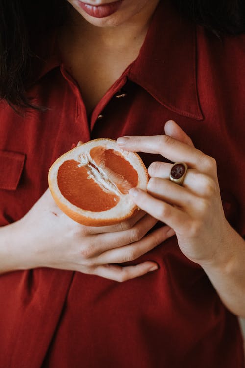 衬衫控股切成薄片的橙色水果的红色按钮的女人 · 免费素材图片