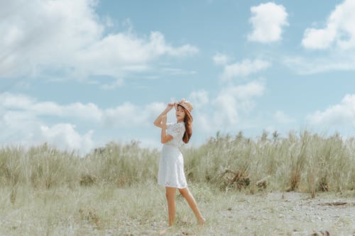 白色和红色的条纹背心站在绿草地上的女人 · 免费素材图片