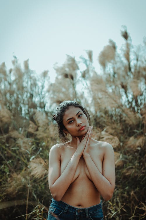 裸照女人坐在棕色的草田 · 免费素材图片