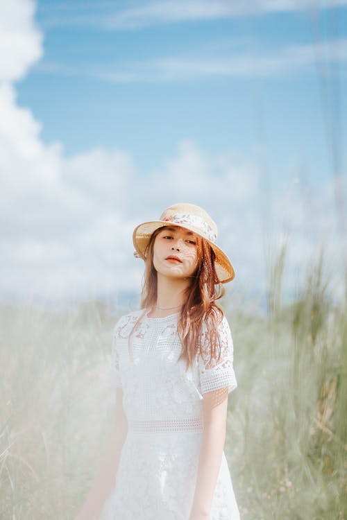 白帽子和白色礼服站在绿草地上的女人 · 免费素材图片