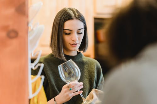 拿着酒杯的灰色毛衣的女人 · 免费素材图片