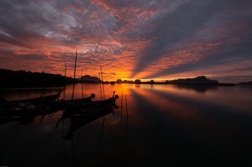 在日落期间在平静的水面上划船 · 免费素材图片