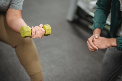 持有黄色和绿色哑铃的人 · 免费素材图片