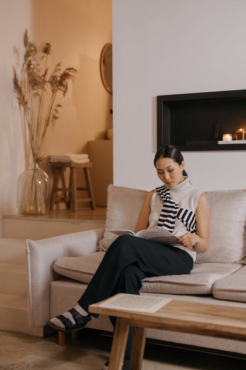 黑色和白色的条纹衬衫，坐在灰色的沙发上的女人 · 免费素材图片