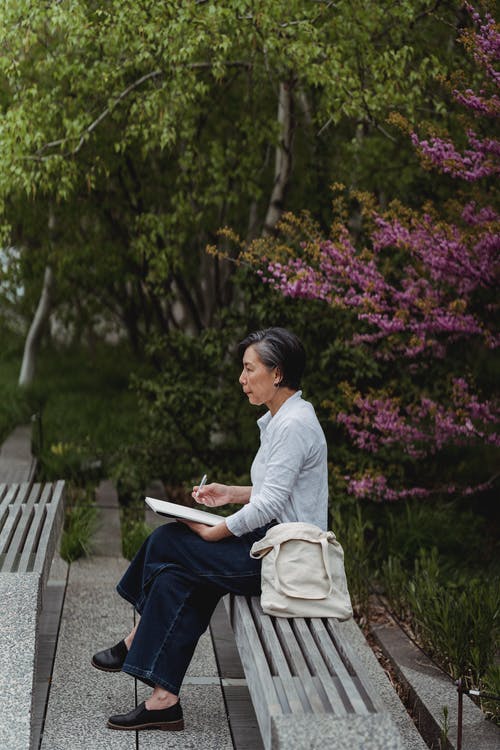 一个女人坐在长凳上思考的侧视图 · 免费素材图片