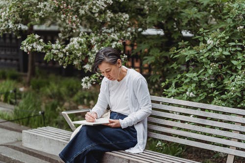 在画板中绘画时坐在长凳上的女人 · 免费素材图片