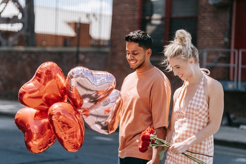 一个男朋友为他的女朋友拿着心形气球 · 免费素材图片