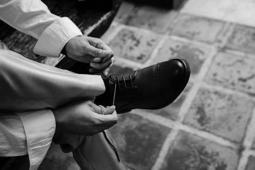 绑鞋的人的单色照片 · 免费素材图片