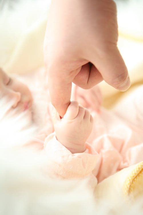 婴儿抱着人的食指 · 免费素材图片