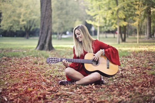 红色的长袖连衣裙，弹着棕色的原声吉他，坐在地上的女人 · 免费素材图片