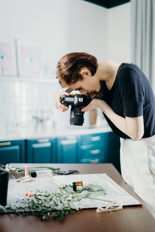 女人穿着黑衬衫在桌子上拍花的照片 · 免费素材图片