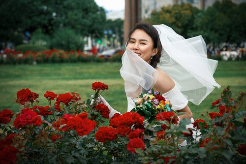 拿着红色花的白色婚礼礼服的妇女 · 免费素材图片