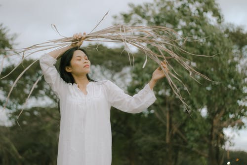 拿着干叶子的白色长袖的女人 · 免费素材图片