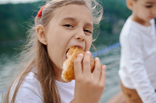 快乐的小女孩，吃美味的牛角包 · 免费素材图片