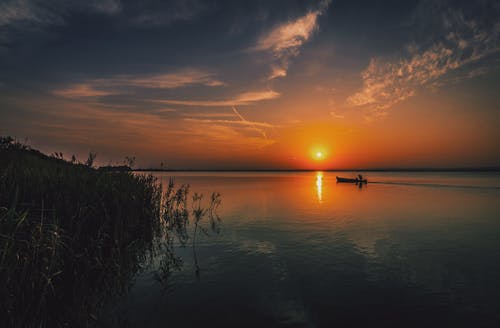 在日落时旅行的船上的人 · 免费素材图片