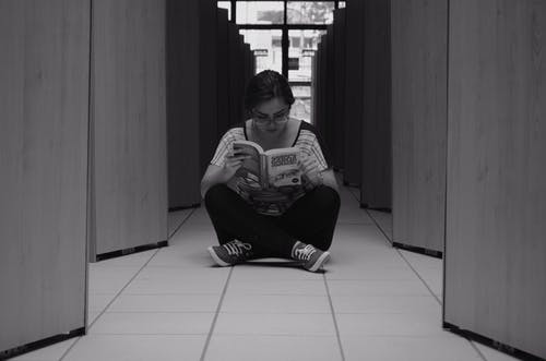 读一本书时坐在地砖上的女人 · 免费素材图片