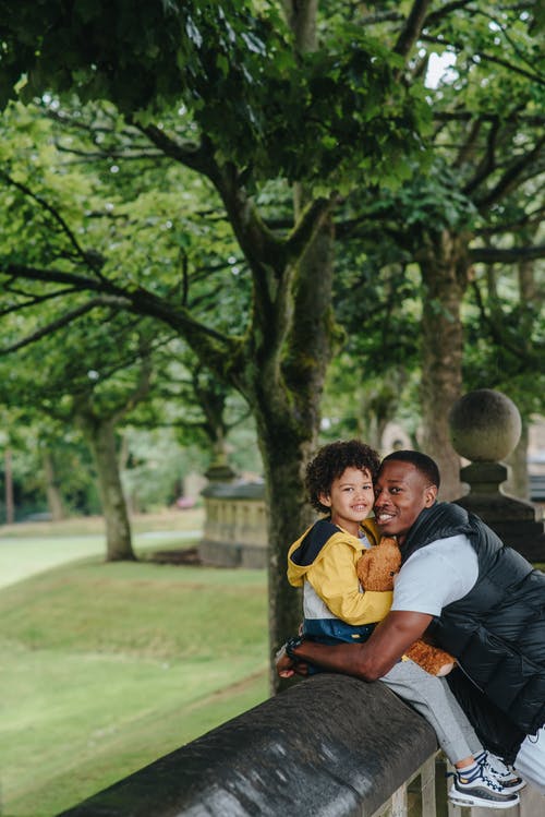 开朗的黑人父亲，在公园里拥抱真诚的男孩 · 免费素材图片