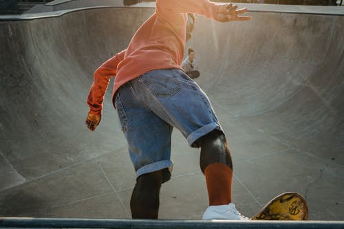 活跃的黑人溜冰者在滑板公园的坡道上表演技巧 · 免费素材图片