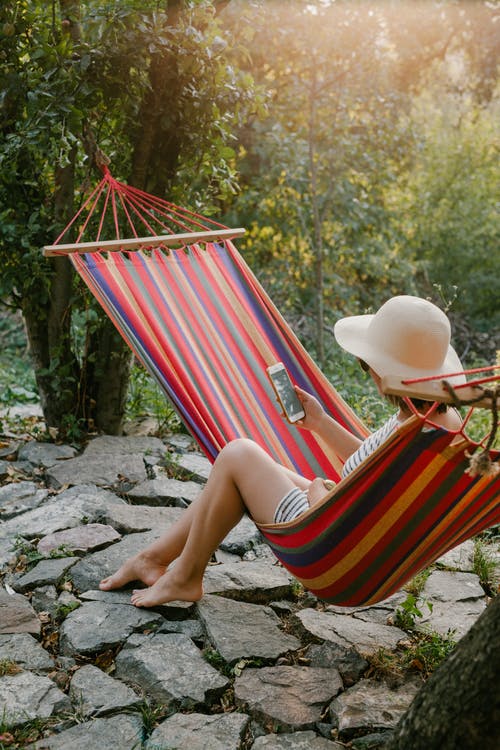 智能手机，坐在吊床上绿色花园的女人 · 免费素材图片