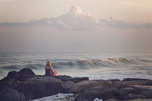 女人坐在海边的岩石上 · 免费素材图片
