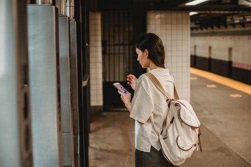 在地铁站中使用智能手机的时尚年轻族裔女人 · 免费素材图片