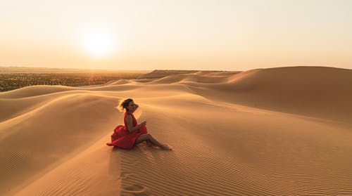 女人坐在沙滩上的照片 · 免费素材图片