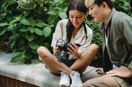 裁剪内容亚洲夫妇坐在公园的相机拍照 · 免费素材图片