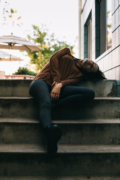 棕色长袖上衣和黑色的裤子，坐在灰色的混凝土楼梯上睡觉的女人 · 免费素材图片