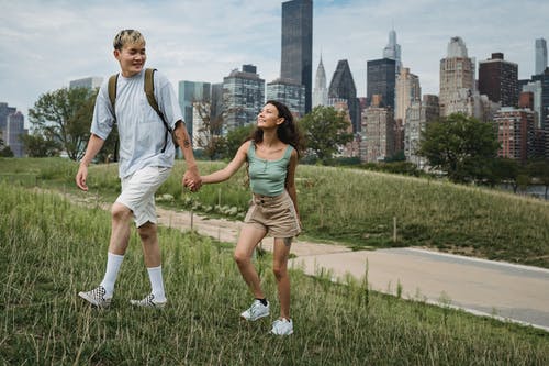 高兴多样的夫妇在城市建筑附近的山坡上漫步 · 免费素材图片