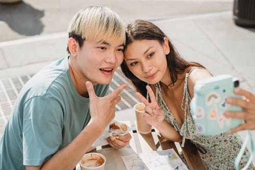 性格开朗的亚洲夫妇在咖啡馆采取自拍照 · 免费素材图片