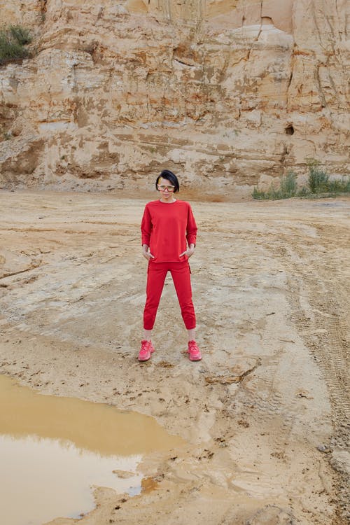 在水坑附近沙漠中穿红衣服的时尚模型 · 免费素材图片