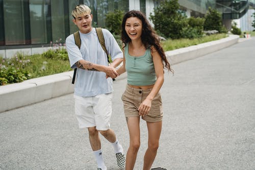 亚裔人在路面上用手拿着种族笑的女朋友 · 免费素材图片