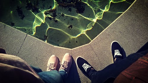 两个人站在水的身体附近拍照的鞋子 · 免费素材图片