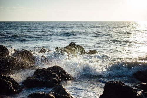 蓝海浪来到多岩石的海岸的照片 · 免费素材图片
