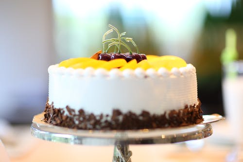 白色圆形蛋糕配上黄色切片水果 · 免费素材图片