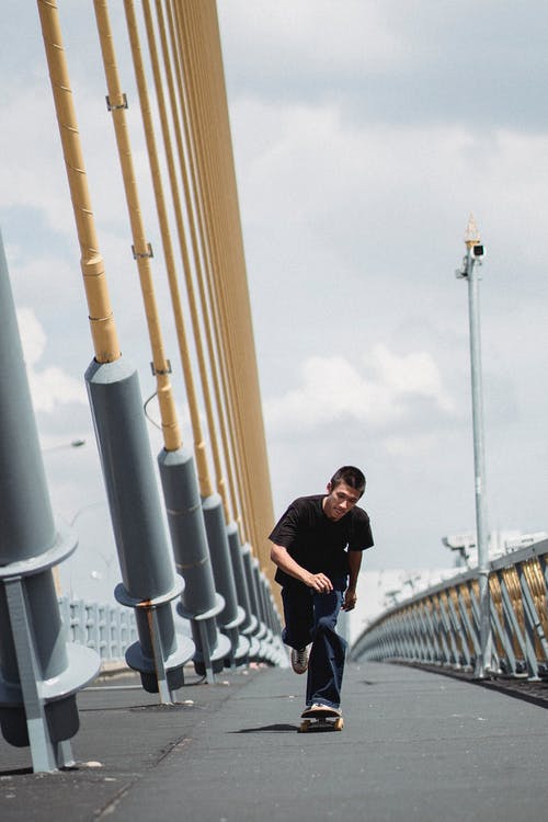 年轻人在桥上骑滑板 · 免费素材图片