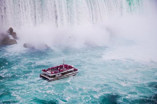 在快速泡沫瀑布附近的河上运送无法识别的旅行者 · 免费素材图片