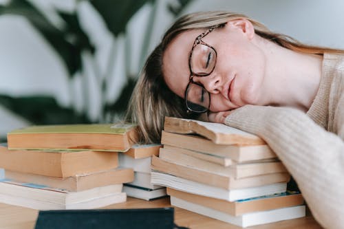 疲惫的女人睡在书堆上 · 免费素材图片