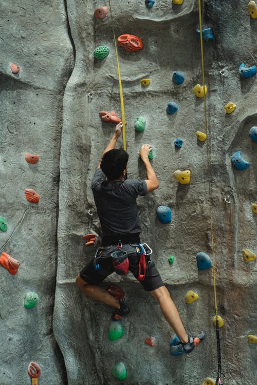 攀岩墙上的匿名运动员训练 · 免费素材图片