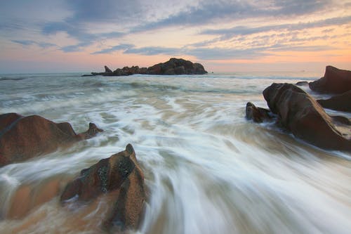 白天在水体附近的棕色岩石 · 免费素材图片