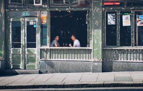 两个男人在商店里互相面对时吃饭 · 免费素材图片