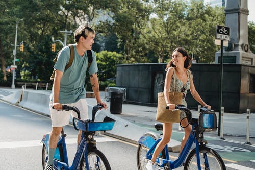 性格开朗的亚洲夫妇在大街上骑自行车 · 免费素材图片