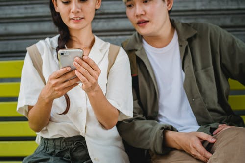 作物亚洲夫妇在长椅上浏览智能手机 · 免费素材图片
