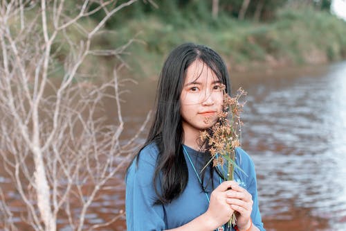 拿着棕色花的妇女佩带的衬衣 · 免费素材图片